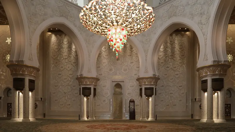 Sala de orações da Grande Mesquita Sheikh Zayed, com lustre dourado de cristais coloridos, arcos brancos e colunas com detalhes florais.
