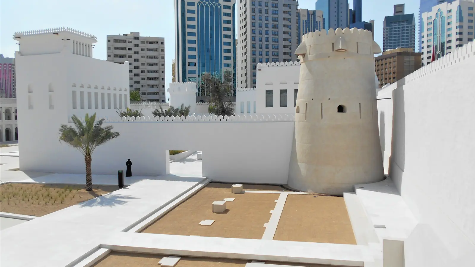 Forte Qasr Al Hosn, com muralhas brancas e torre redonda de pedra clara, em contraste com os prédios modernos do centro de Abu Dhabi.